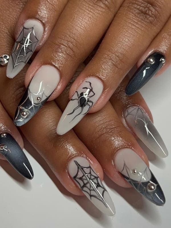 Long-almond-grey-and-silver-spider-nails-with-misty-ombre-bases,-metallic-silver-cobwebs,-3D-spider-charms,-and-silver-stud-accents.