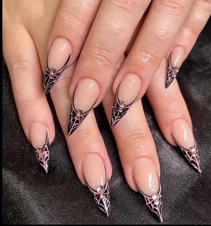 Spider-web-nails-french-tip-featuring-long-stiletto-acrylics,-a-nude-base,-black-V-cut-french-tips-with-pink-cobweb-art,-and-pink-rhinestone-accents.
