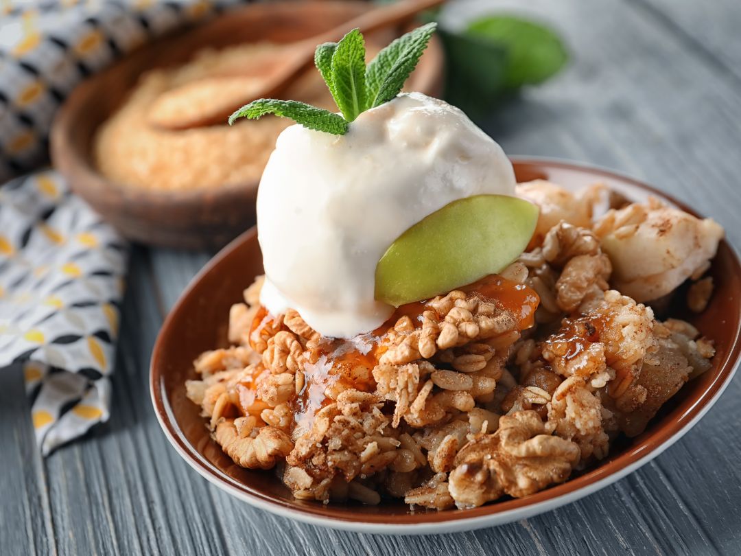 homemade-fall-apple-crisp-dessert-served-with-vanilla-ice-cream-on-a-brown-plate