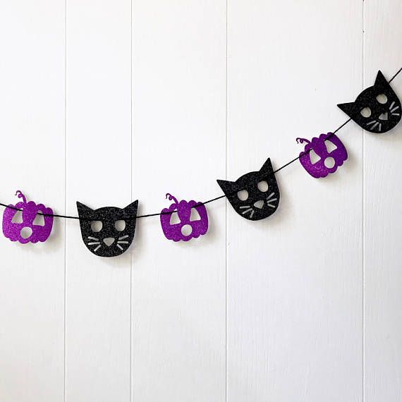 glittery-black-cat-head-and-purple-pumpkin-garland-against-white-paneling