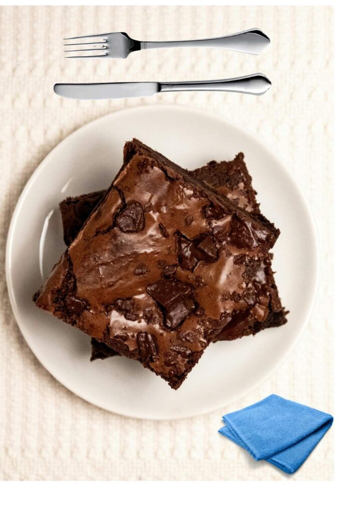 fudgy-chocolate-brownies-stacked-on-a-white-plate-with-a-fork-knife-and-folded-napkin-easy-thanksgiving-potluck-ideas