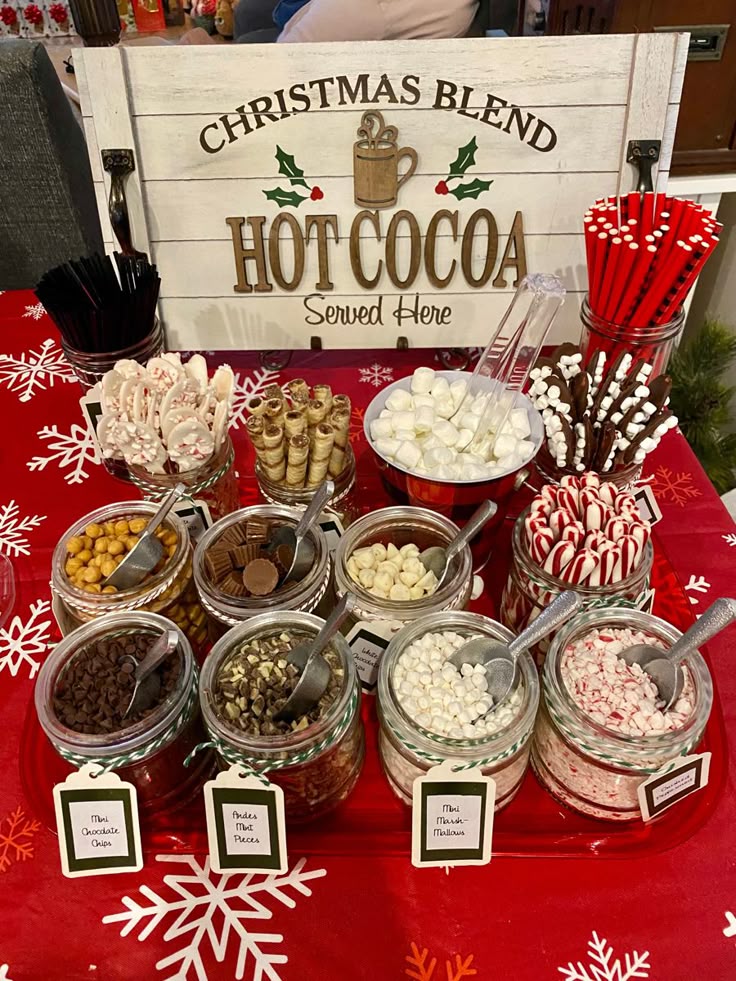A-festive-hot-chocolate-bar-table-with-glass-jars-of-toppings,-marshmallows,-candy-canes,-and-a-wooden-sign.