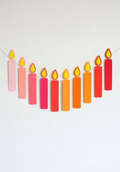 colorful-gradient-paper-candle-cutout-garland-hanging-against-white-wall