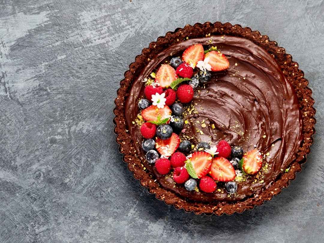 chocolate-bourbon-tart-topped-with-fresh-berries-against-a-gray-background