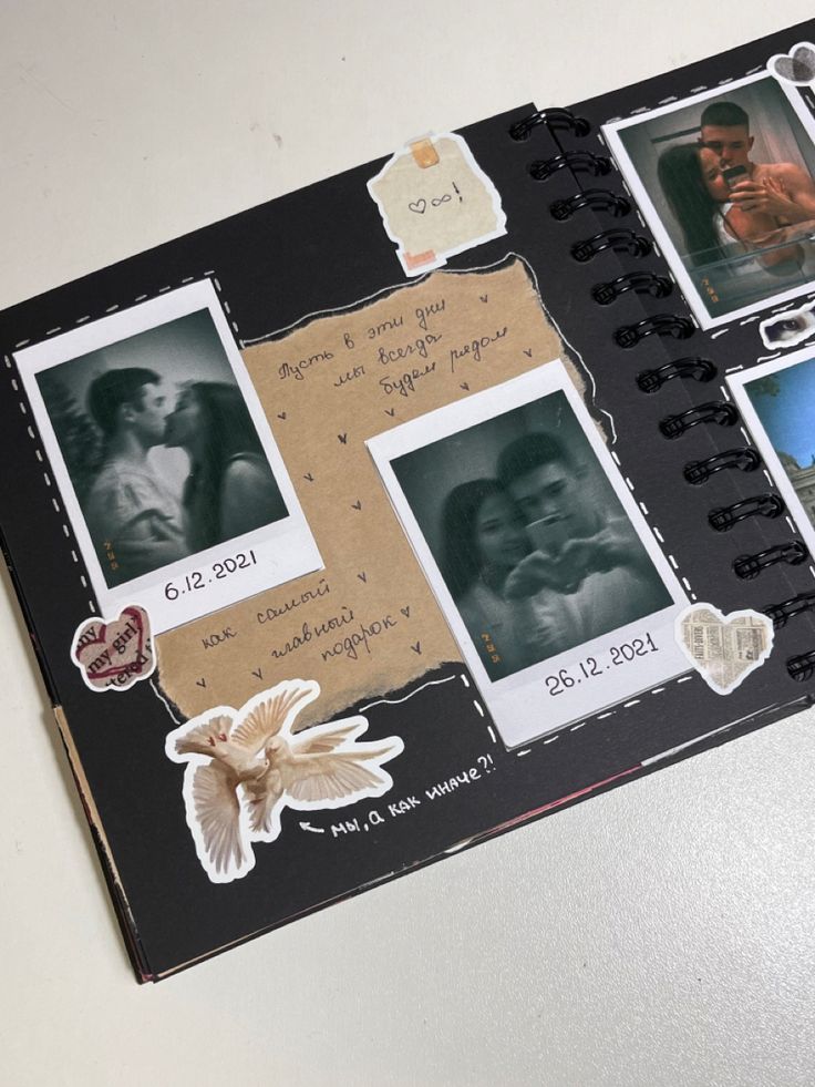 An-open-scrapbook-with-photos-of-a-couple,-written-messages-and-stickers-of-doves-and-hearts.