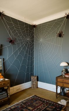 giant-yarn-spider-webs-stretching-across-a-room-corner-wall-decorated-with-large-black-spiders