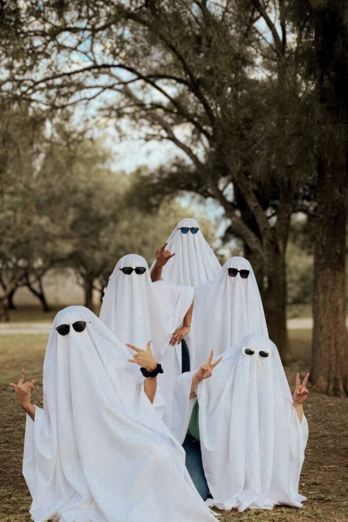 group-wearing-classic-white-sheet-ghost-costumes with-sunglasses-posing-outdoors