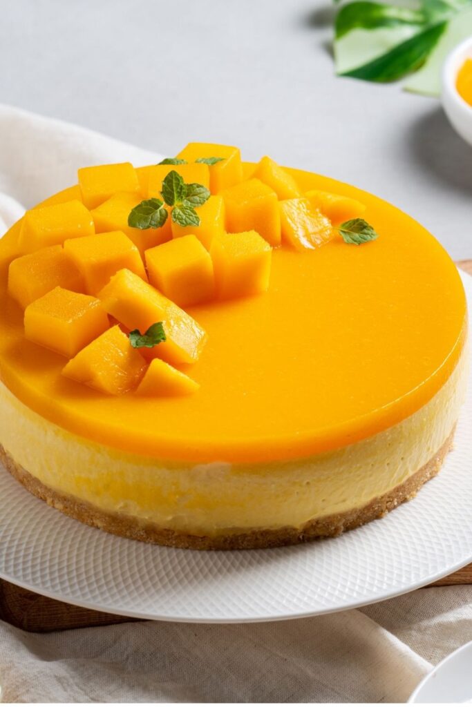 no-bake-cheesecake-topped-with-fresh-diced-mango-pulp-served-on-a-white-plate -for-thanksgiving-desserts-that-aren't-pumpkin-pie 