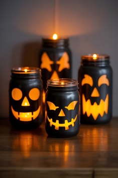 black-painted-mason-jar-candle-holders-with-carved-jack-o-lantern-face-cutouts-glowing