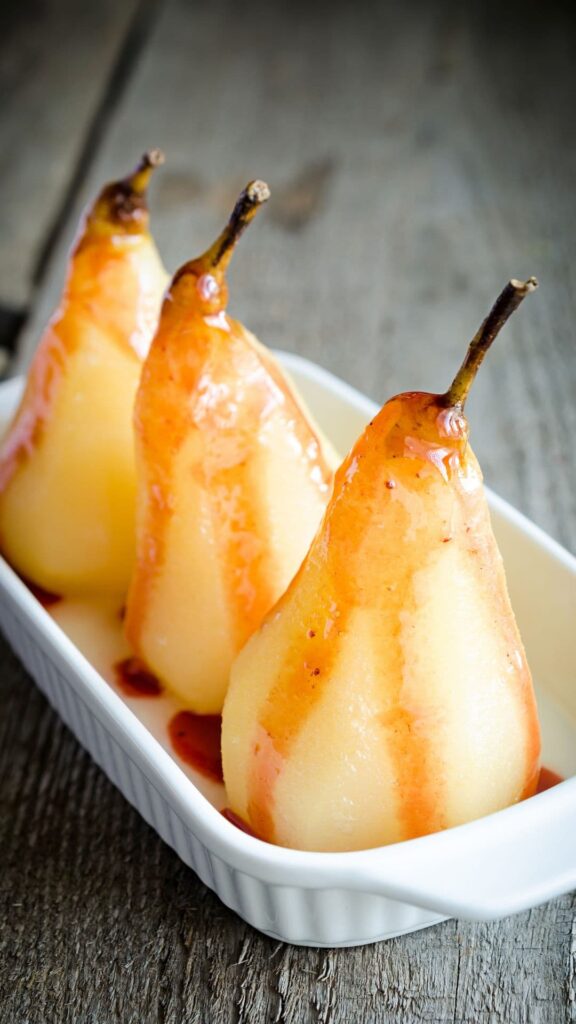 three-whole-poached-pears-drizzled-with-caramel-sauce-arranged-in-a-white-ceramic-baking-dish