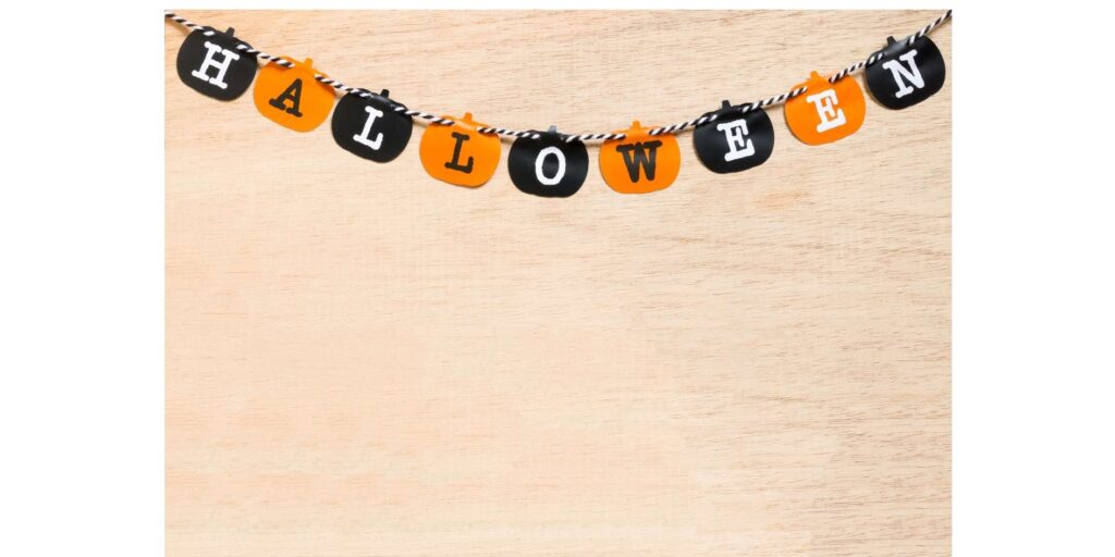 pumpkin-shaped-halloween-letter-banner-spelling-halloween-hanging-against-a-light-wooden-wall