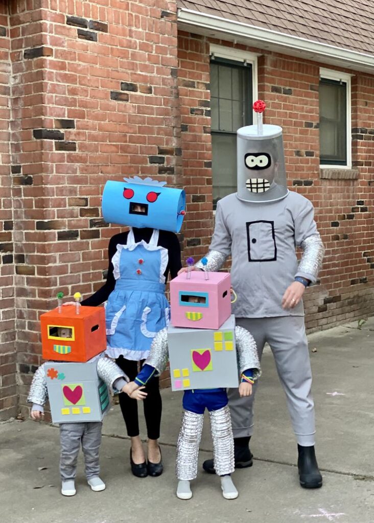 family-dressed-in-diy-cardboard-box-robot-costumes-with-colorful-masks-and-tin-foil-limbs