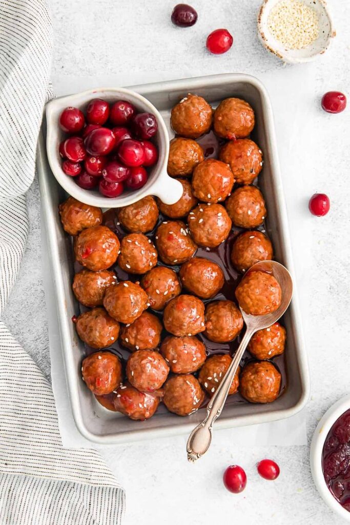 slow-cooker-cranberry-cocktail-meatballs-in-a-baking-dish-with-fresh-cranberries-easy-christmas-party-potluck-ideas 