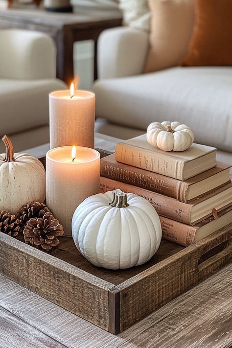 cozy-wooden-tray-on-a-coffee-table-styled-with-white-pumpkins-stacked-vintage-books-pinecones-and-glowing-candles