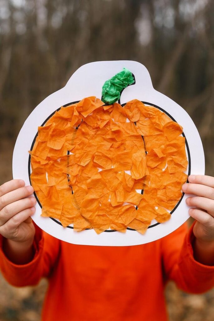 child-holding-a-paper-pumpkin-craft-filled-with-orange-and-green-tissue-paper