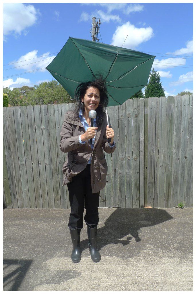 a-woman-with-umbrella-and-microphone-replicating-a-weather-reporter