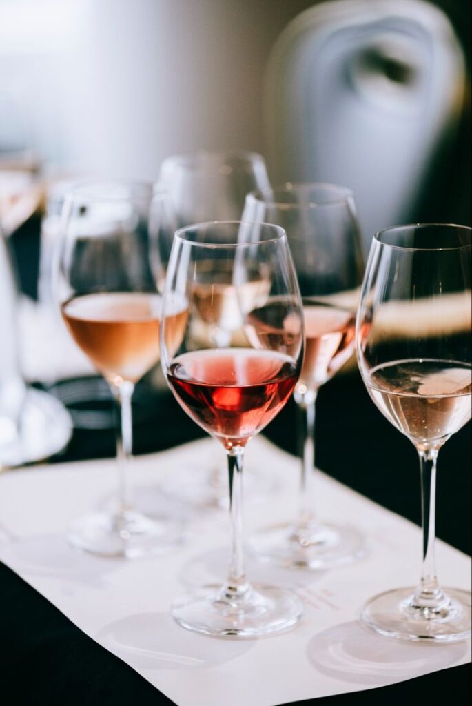 Four-glasses-of-different-rosé-and-white-wines-lined-up-for-a-tasting-experience-on-a-white-mat.