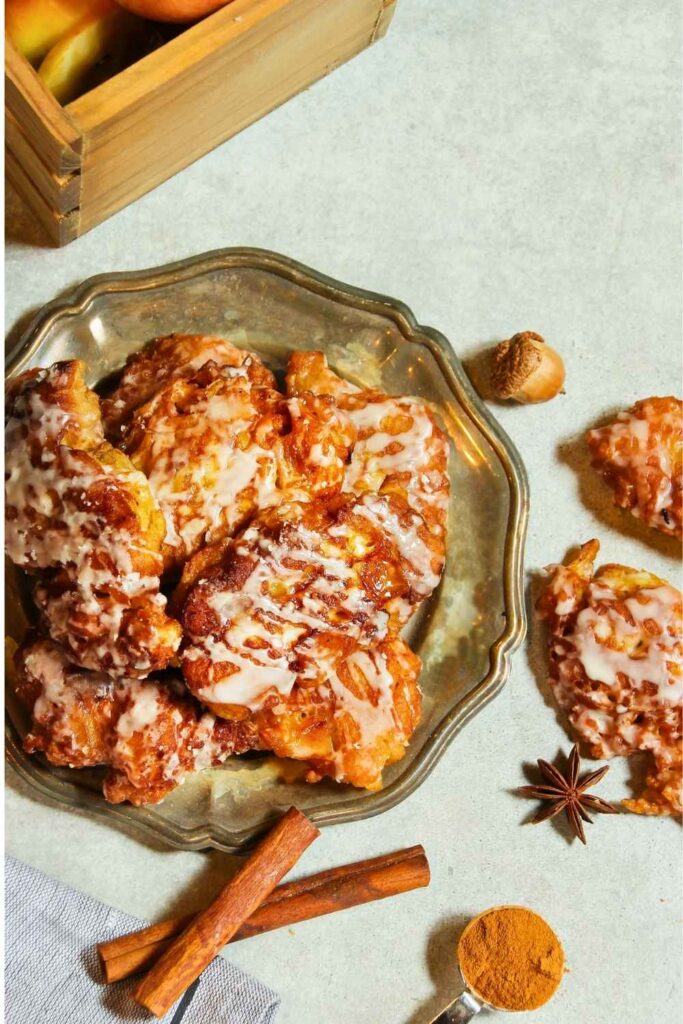 glazed-baked-apple-fritters-on-a-silver-platter-with-cinnamon-sticks-and-ground-cinnamon