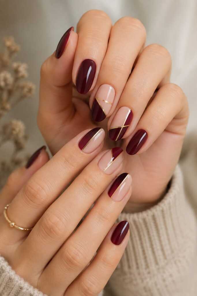 glossy-burgundy-and-nude-color-block-oval-nails-with-gold-striping-tape-fall-nail-designs