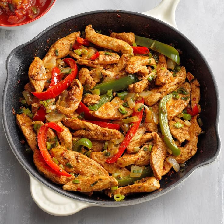 sizzling-chicken-fajita-strips-with-red-and-green-bell-peppers-and-onions-in-a-black-skillet