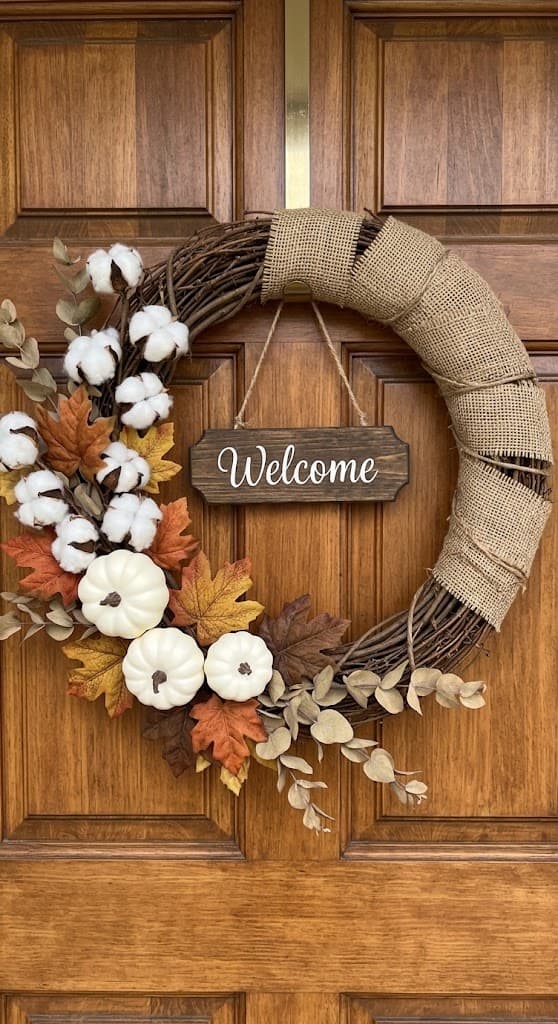 farmhouse-burlap-wrapped-grapevine-wreath-with-cotton-stems-mini-white-pumpkins-autumn-leaves-and-wooden-welcome-sign-on-wooden-door