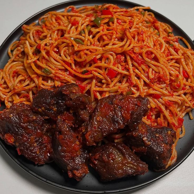 spicy-jollof-spaghetti-served-on-a-black-plate-with-stewed-beef
