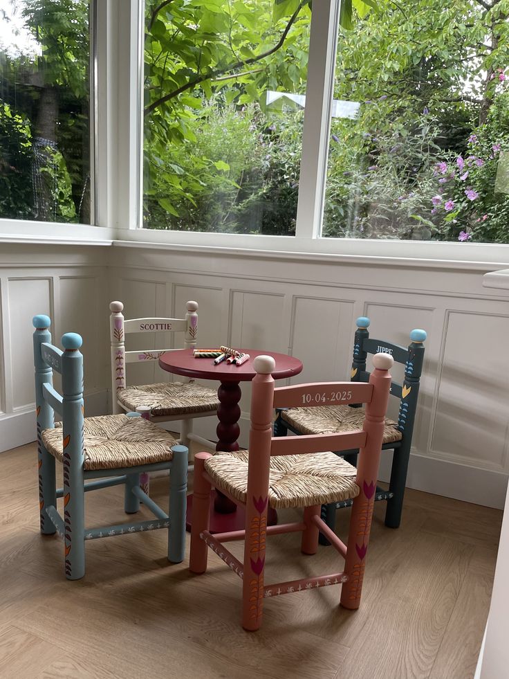 hand-painted-wooden-childrens-table-and-spindle-chairs-set-by-a-window-with-greenery-in-a-vintage-style-room