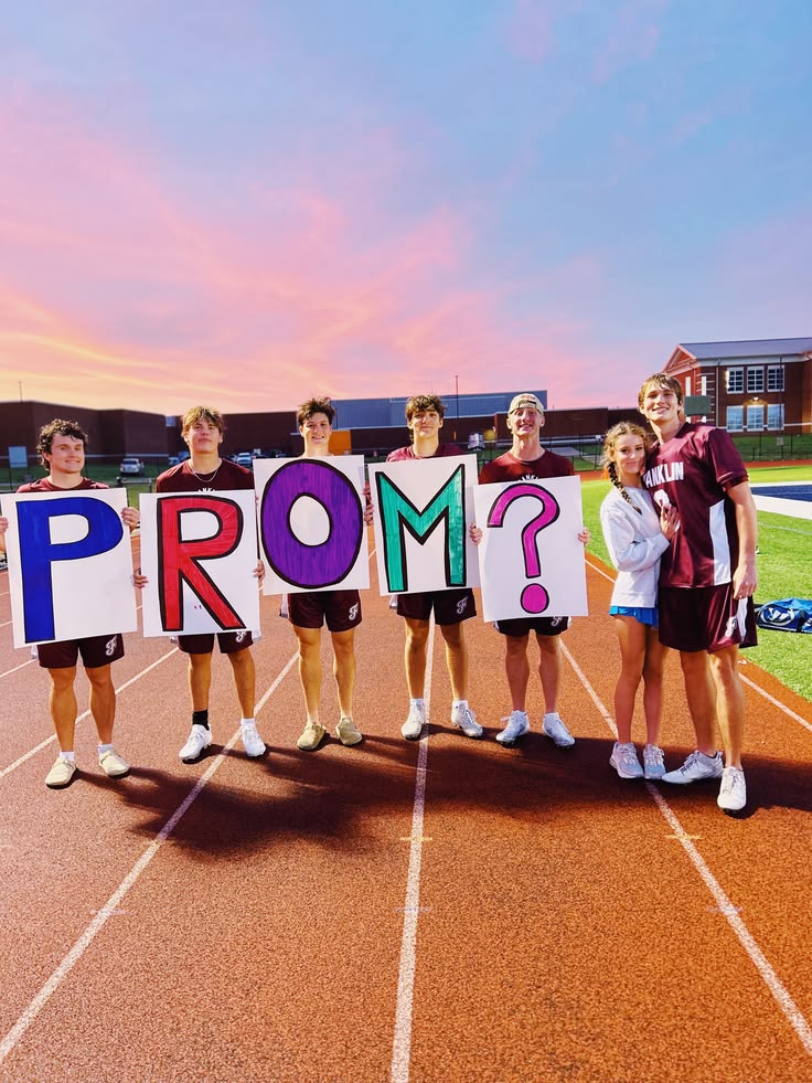 friends-holding-colorful-prom-letter-signs-on-running-track