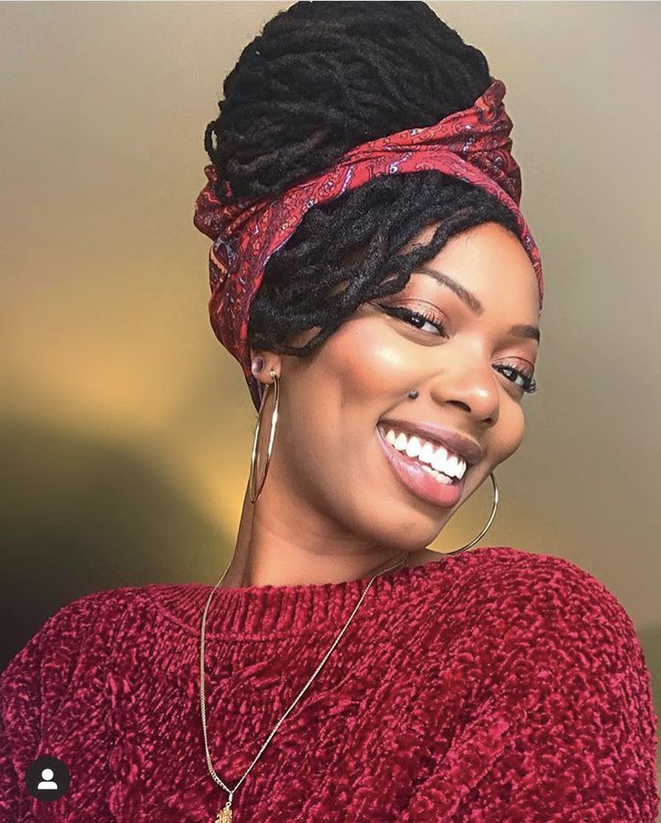 smiling-woman-wearing-a-red-top-and-locs-styled-in-a-high-bun-with-a-printed-red-headwrap