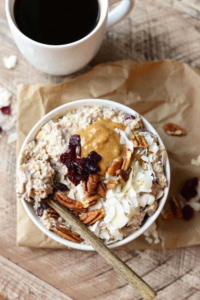 overnight-oats-topped-with-dried-cranberries-pecans-coconut-flakes-and-nut-butter-served-with-black-coffee-thanksgiving-breakfast-ideas