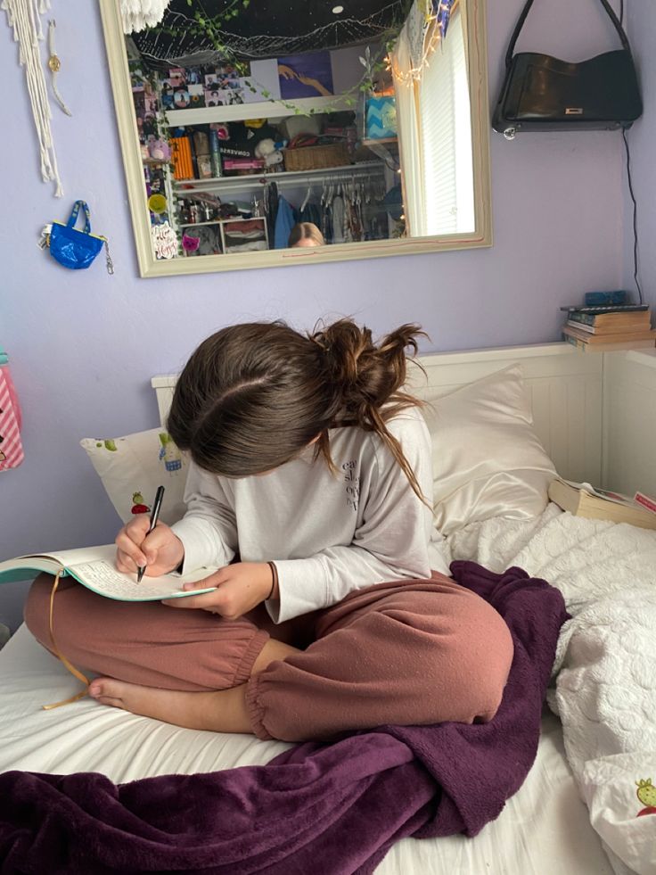 person-sitting-cross-legged-on-a-bed-writing-in-a-journal