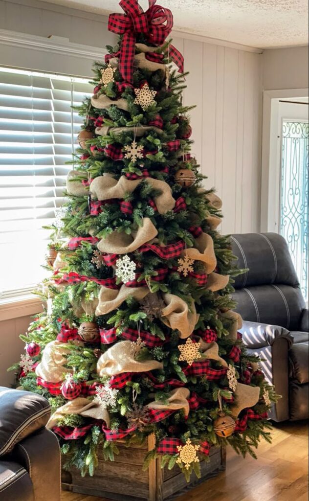 rustic-farmhouse-christmas-tree-decorated-with-burlap-garland-red-plaid-ribbon-wooden-snowflakes-and-a-wooden-crate-base